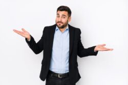 Man shrugging as he stands against neutral background