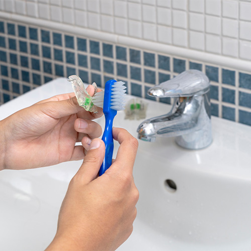 Person using a soft brush to clean their oral appliance
