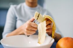 Person cutting a banana, preparing to eat it