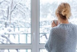 Woman looking out her window at winter landscape