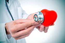 Doctor holding stethoscope against representation of a heart 